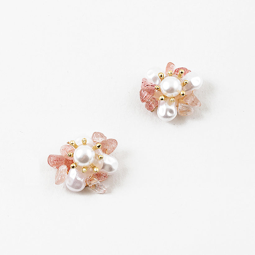 A pair of gold-colored earrings adorned with white pearls and pink accents.