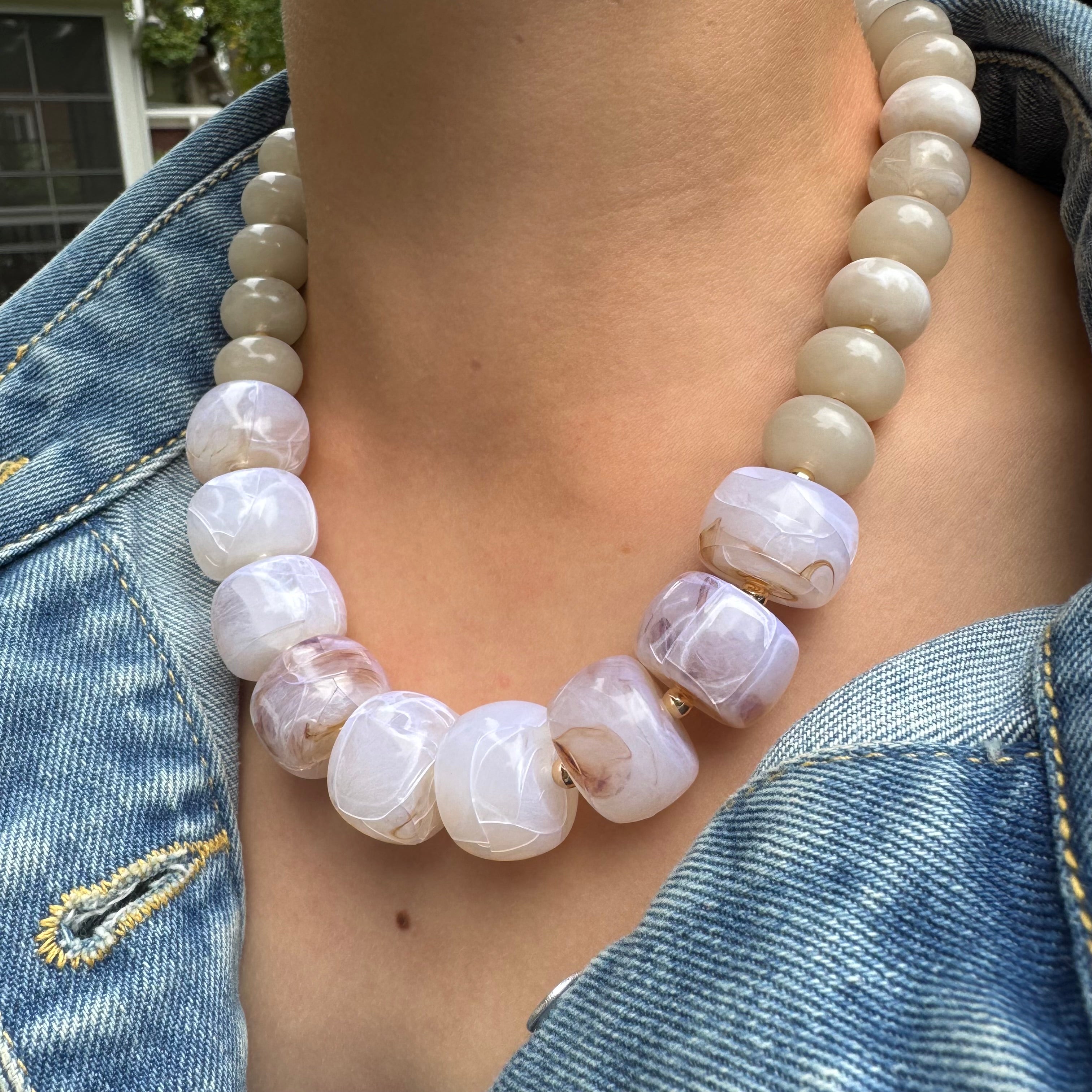 Necklace with large white beads worn by a person against a denim background