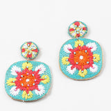 Colorful embroidered dangle earrings in turquoise, orange, coral and White on a white background