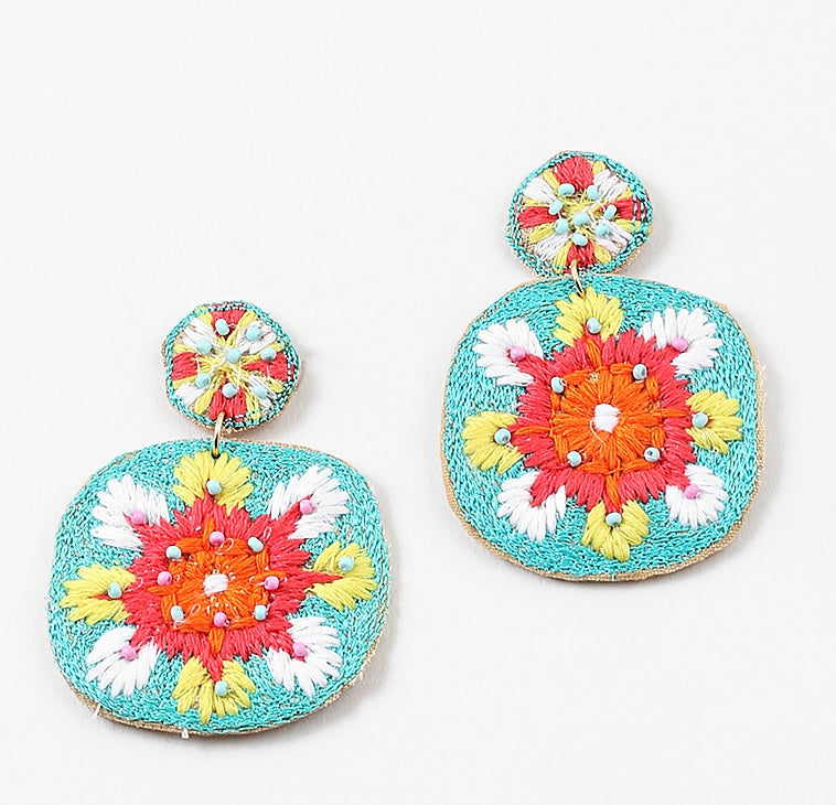 Colorful embroidered dangle earrings in turquoise, orange, coral and White on a white background