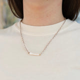 Picture of model wearing a brown and white braided necklace with an elongated fresh water pearl bead.