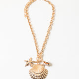 Picture of a gold chain necklace with three large sea pendants. Pendants are a large clam seashell, a smaller gold starfish and a small cowry shell.