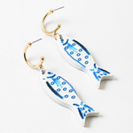 Picture of small gold hoops with white fish with blue details hanging from them.