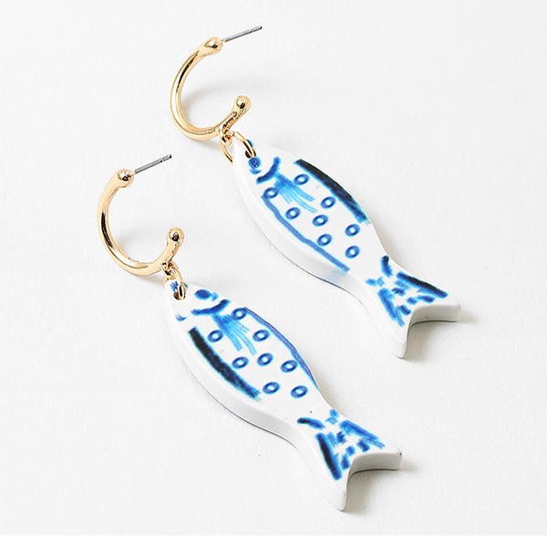 Picture of small gold hoops with white fish with blue details hanging from them.