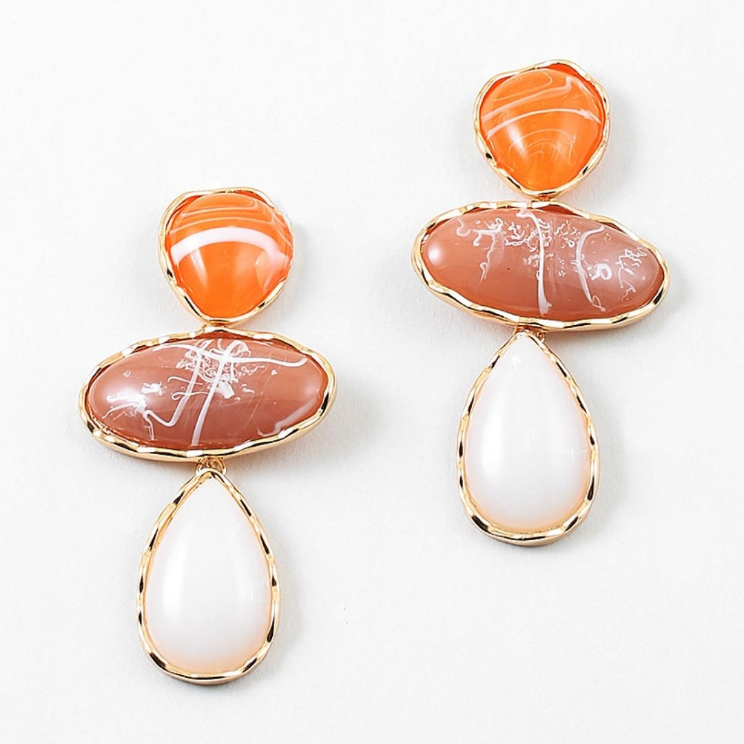 Pair of large dangle earrings with orange, pink, and white stone drops on a white background