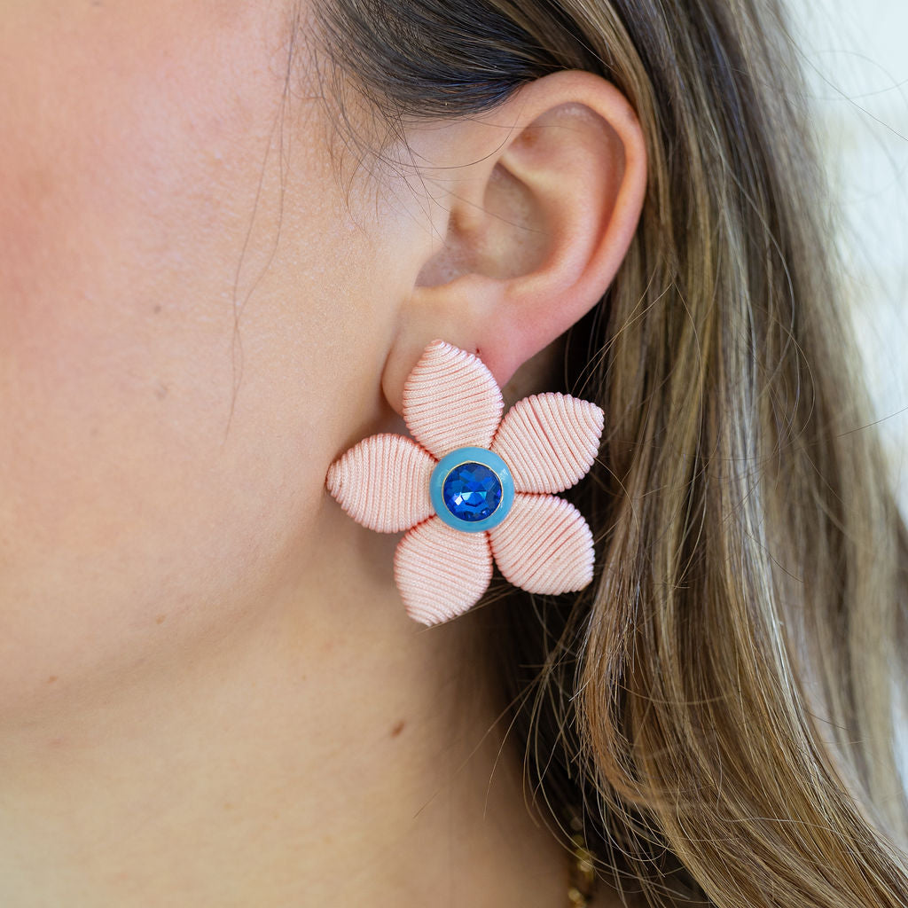 Picture of light colored woven flower earring with a blue diamond center.