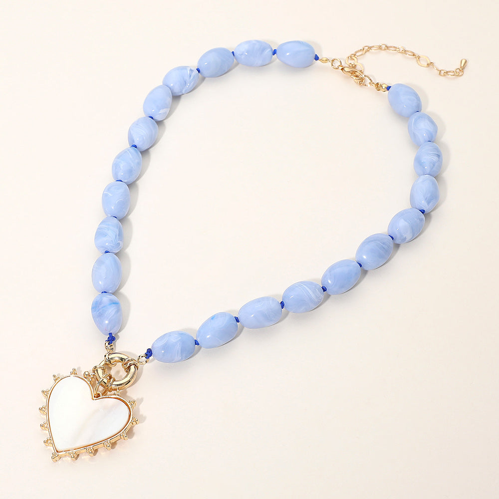 A necklace with blue beads and a heart-shaped charm in a metallic finish, with a toggle clasp.