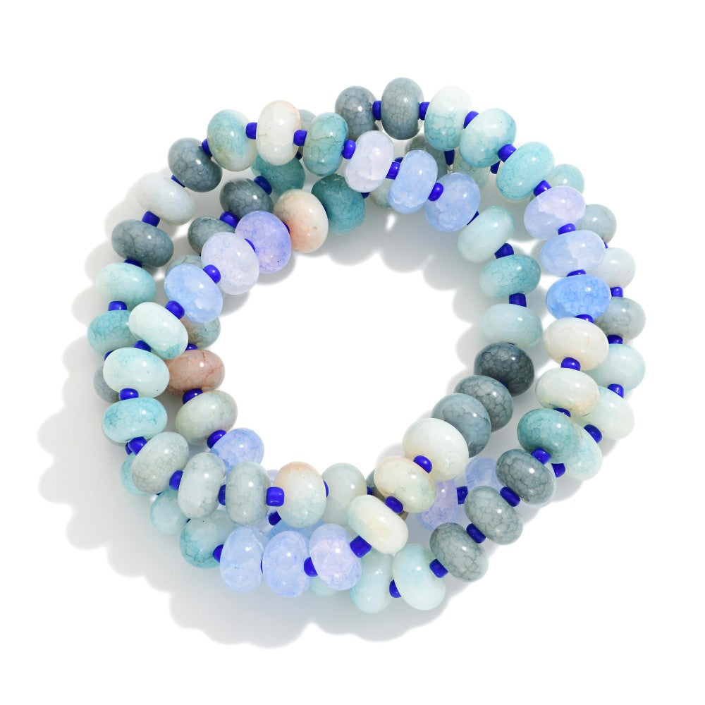 Set of blue and green multicolored beaded bracelets on a white background