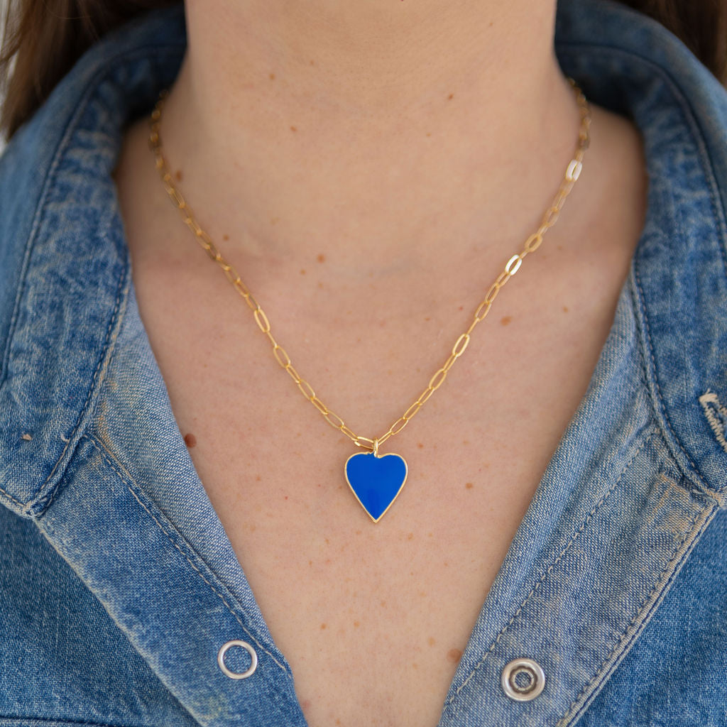 Person wearing a gold chain with a blue enamel heart pendant