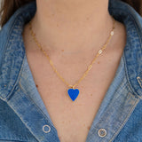 Person wearing a gold chain with a blue enamel heart pendant