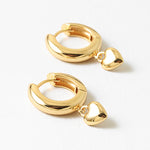 Gold hoop earrings with heart charms on a white background