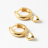 Gold hoop earrings with heart charms on a white background