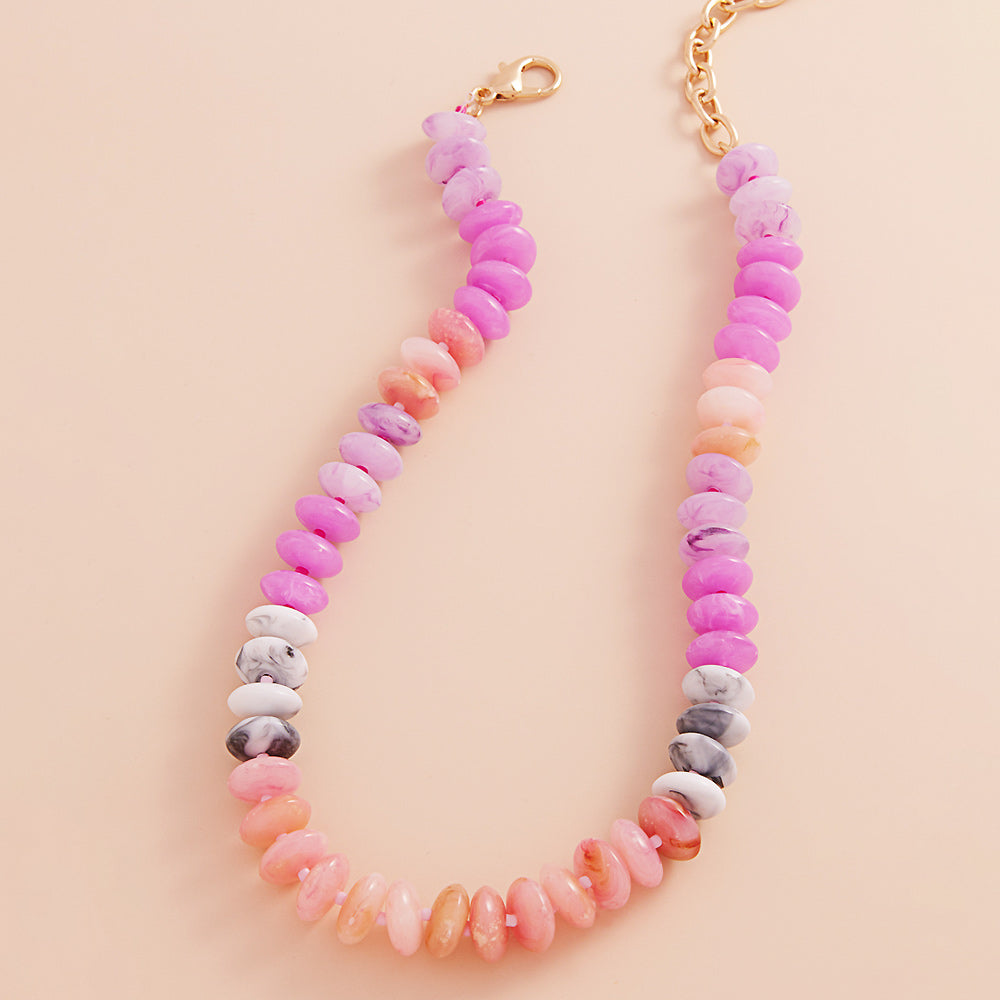 Necklace with pastel-colored pink and coral beads on a beige background