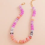 Necklace with pastel-colored pink and coral beads on a beige background