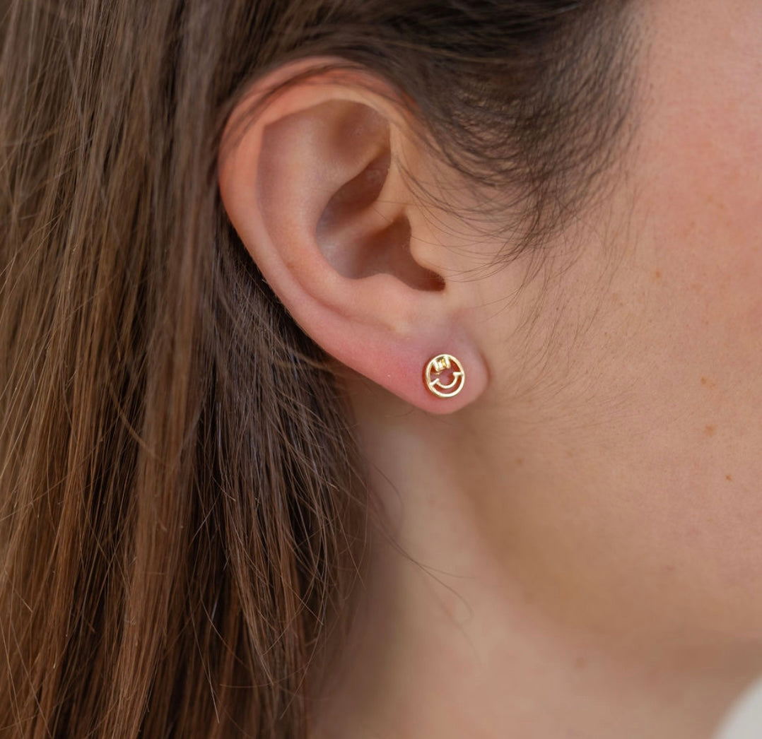 Picture model wearing a small smiley face gold stud.