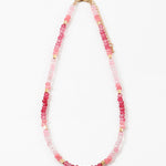 Necklace with pink beads and gold accents on a white background