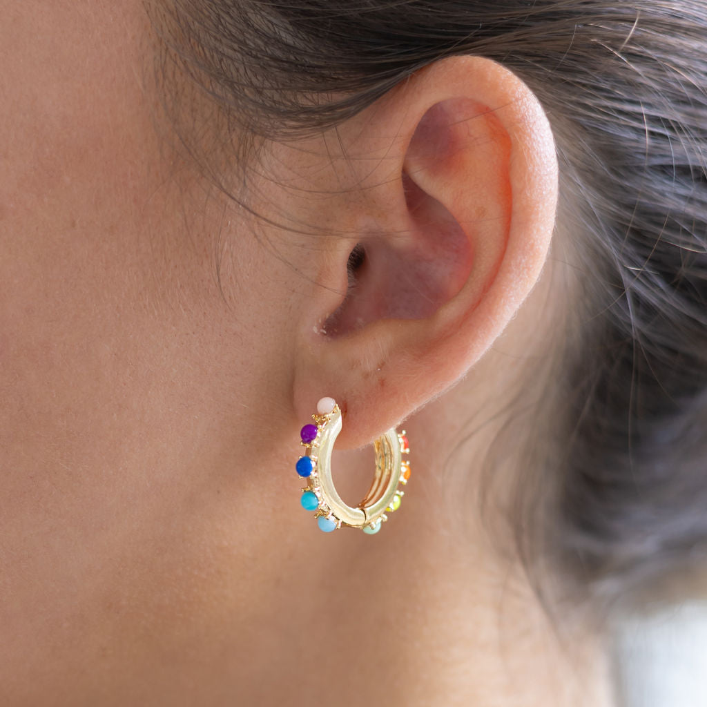 Woman wearing white hoop earrings with colorful gemstones on it
