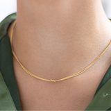 Model wearing dainty gold necklace with a petite knot in the center