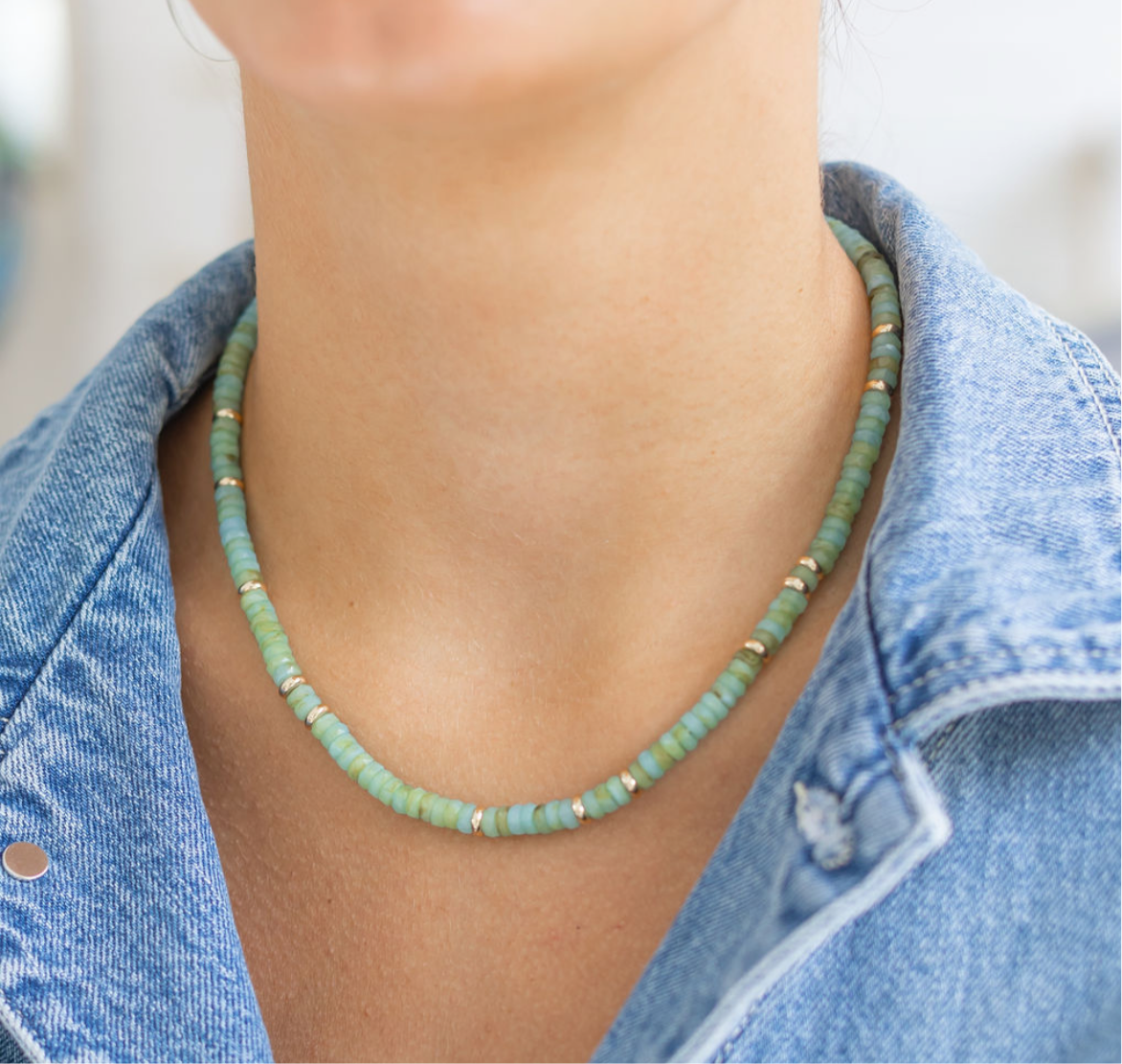 Person wearing a green beaded necklace with a denim jacket