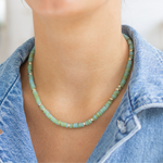 Person wearing a green beaded necklace with a denim jacket