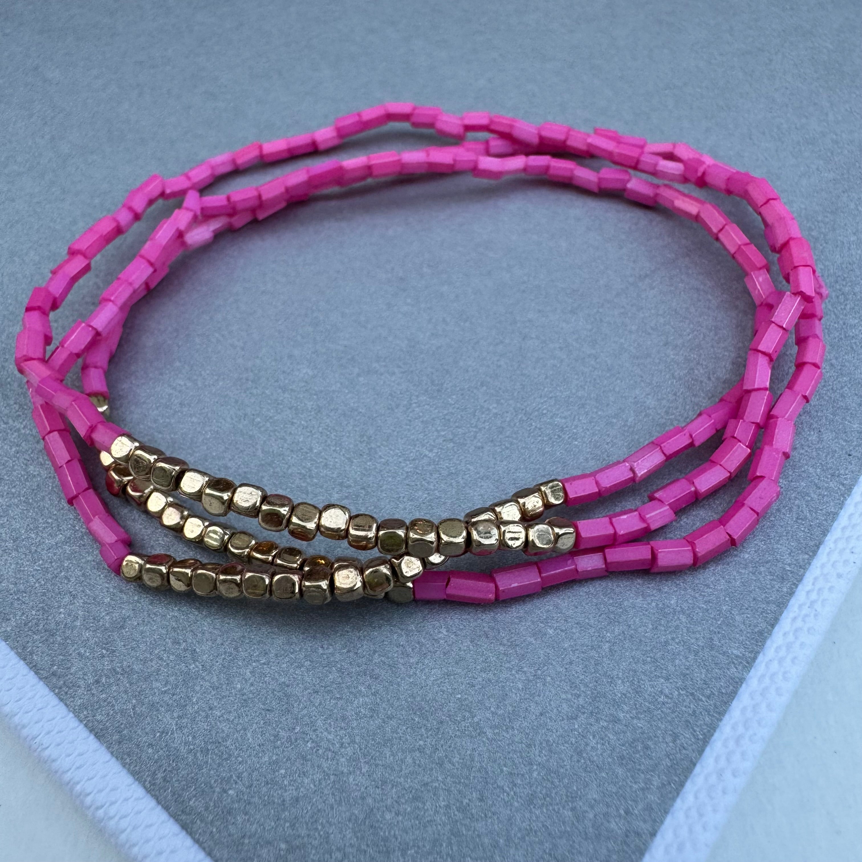 Set of three pink seed bead bracelets with sections of gold beads.