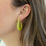 Picture of a woman's ear displaying a large, thick, resin yellow fish hook earring.