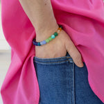 Colorful beaded bracelet on a wrist with a pink fabric background
