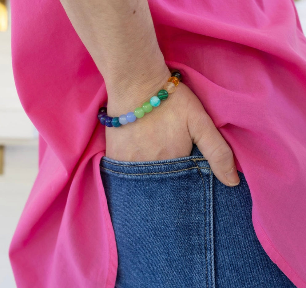 Colorful beaded bracelet on a wrist with a pink fabric background