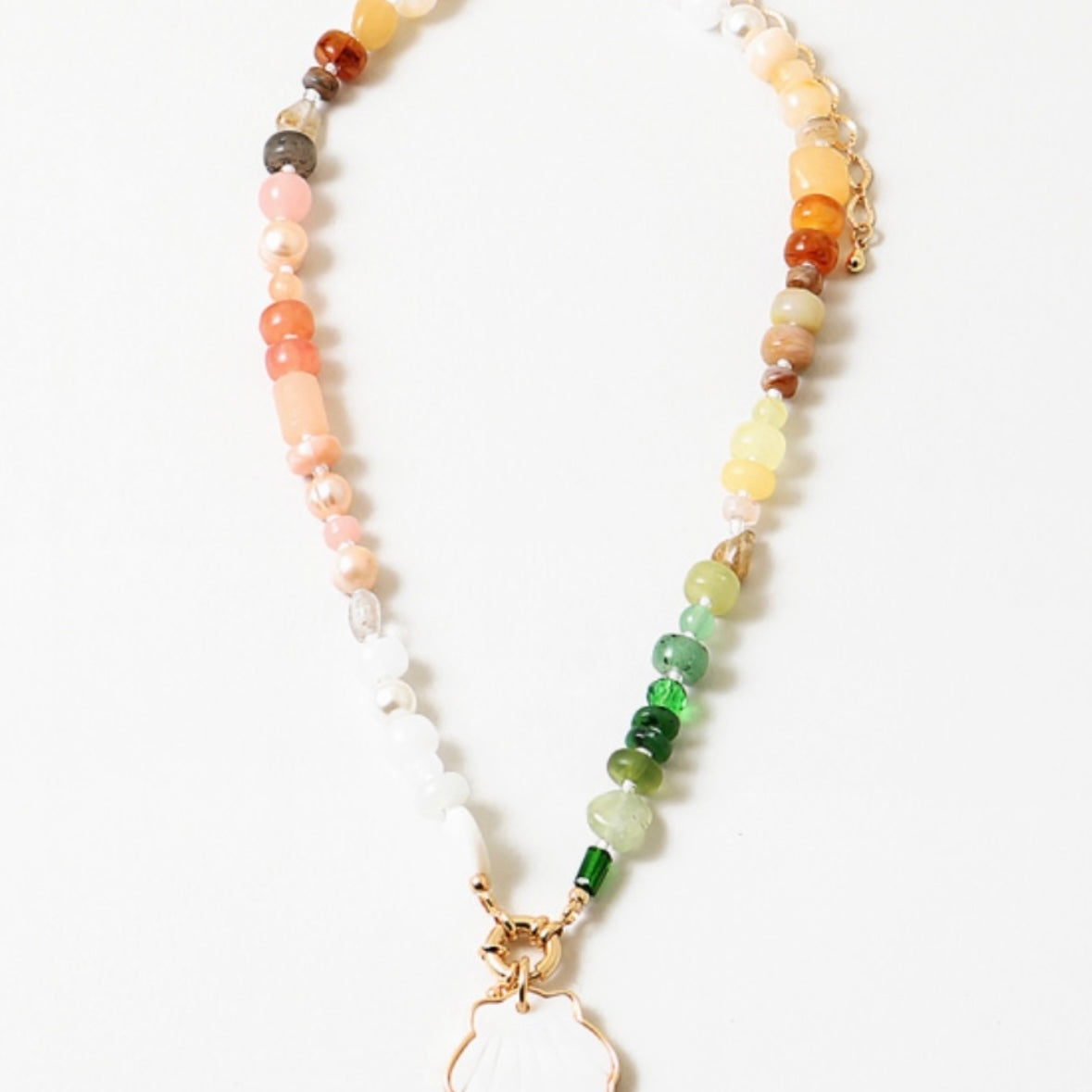 A necklace with multicolored resin beads and a stone pendant, featuring a shell shape, strung together with gold-colored metal rings.