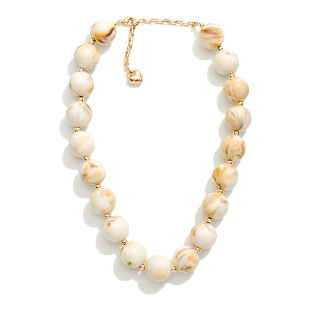 Beaded necklace with cream-colored beads and gold accents on a white background
