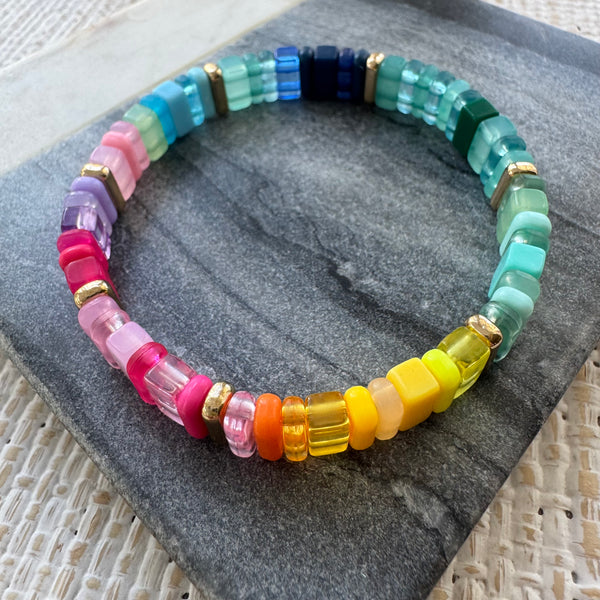 Picture of a multicolored rectangular beaded bracelet in clear and solid colors. Colors are greens, blues, pinks, purples and yellows.