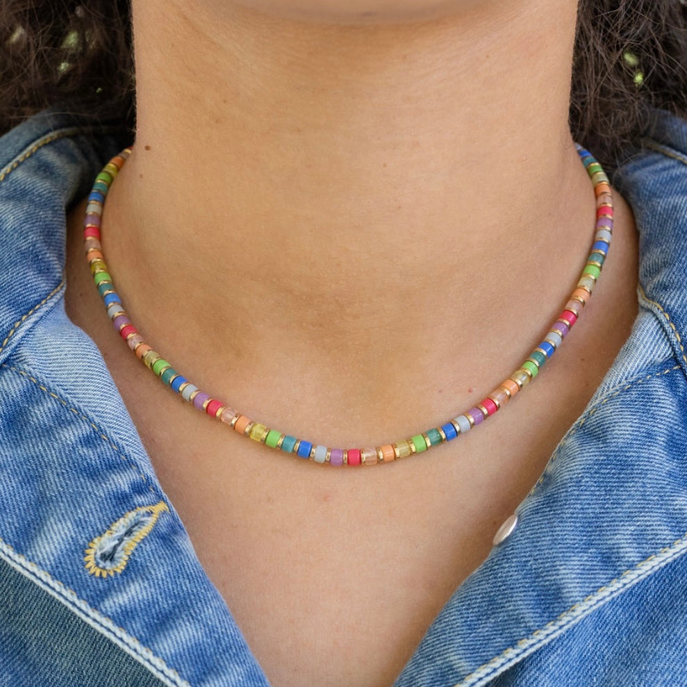 Colorful beaded necklace worn by a person with a denim jacket.