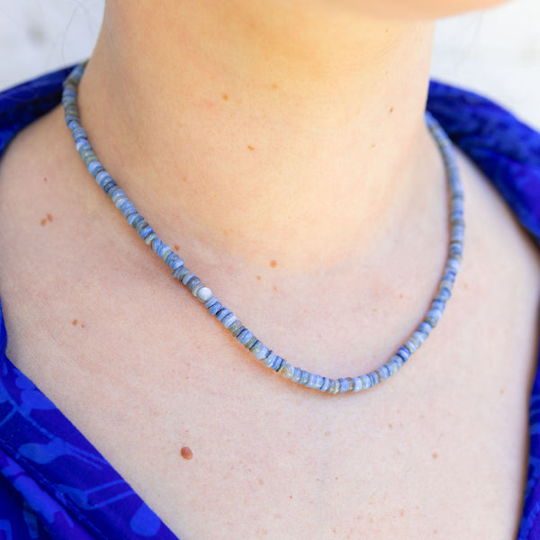 Woman wearing a blue multi-colored beaded short necklace/choker around her neck