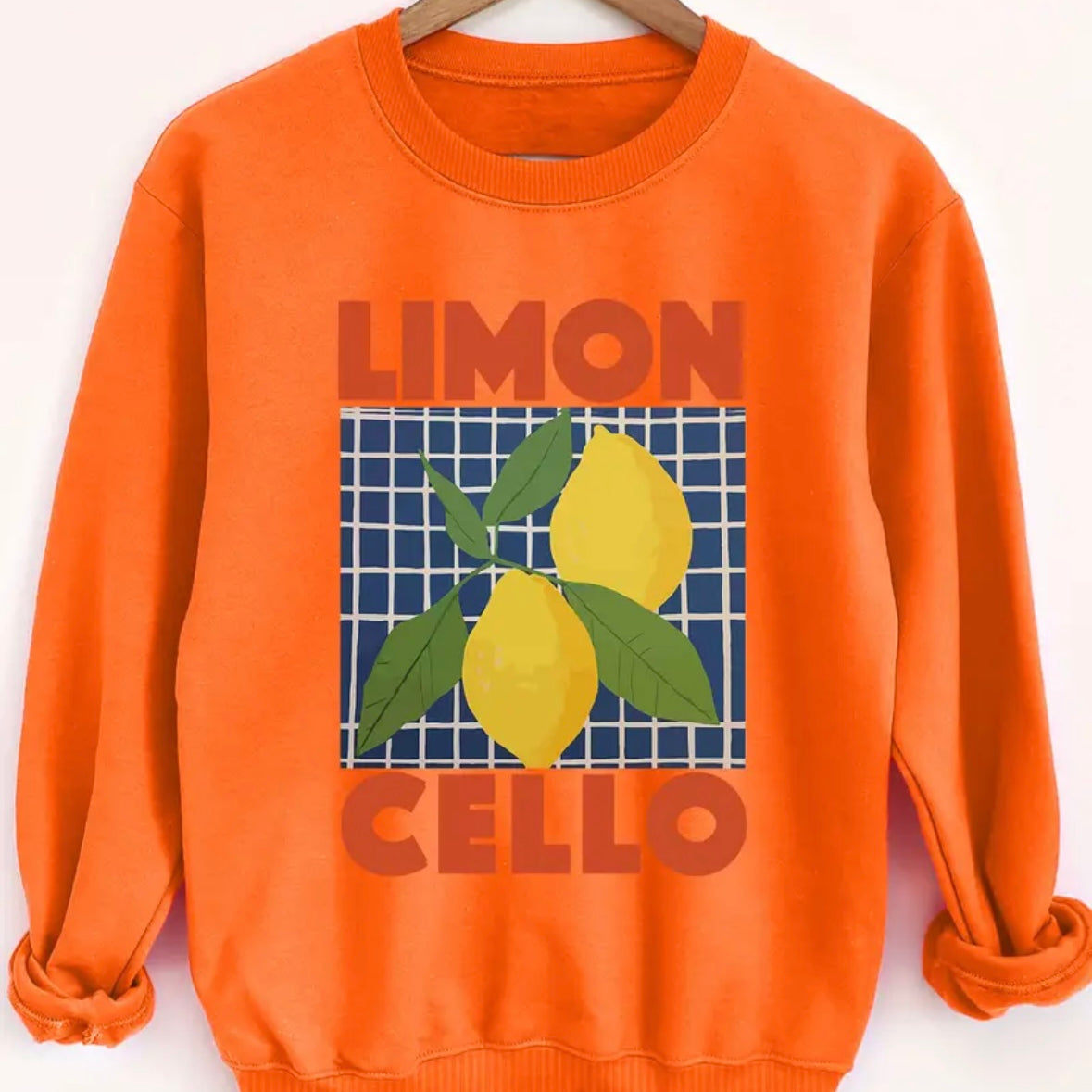 Orange sweatshirt with 'Limon Cello' and lemons design on a hanger