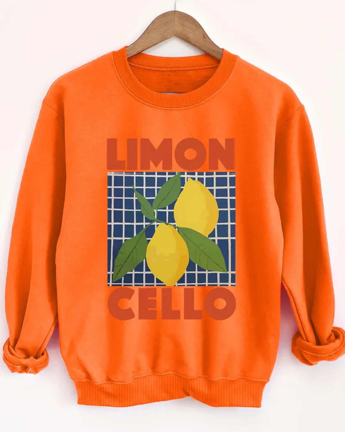 Orange sweatshirt with 'Limon Cello' and lemons design on a hanger