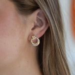 Close-up of a person wearing a gold hoop earring with a blurred background