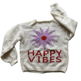Picture of a cream colored sweater with a purple flower with a red center and red lettering that read, "Happy Vibes".