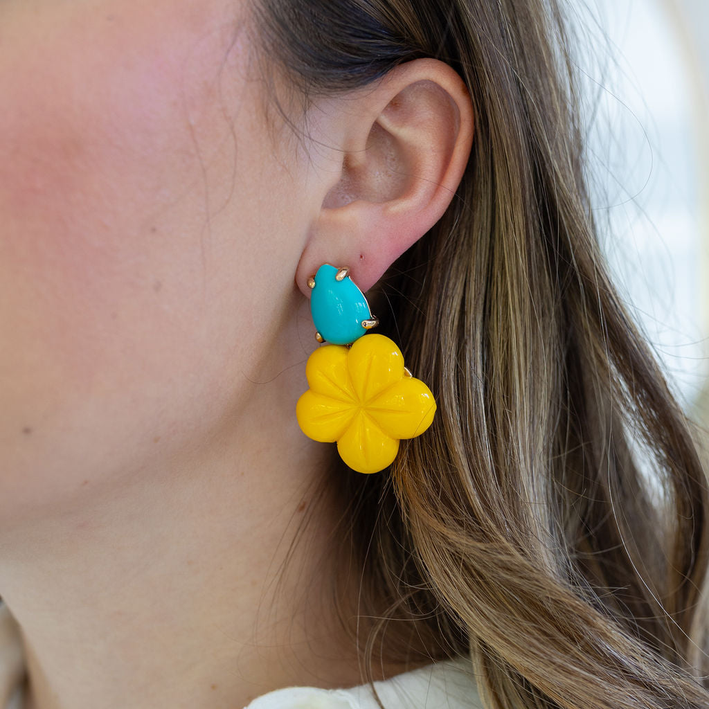 Picture of a woman wearing yellow flower earrings topped with a turquoise teardrop.