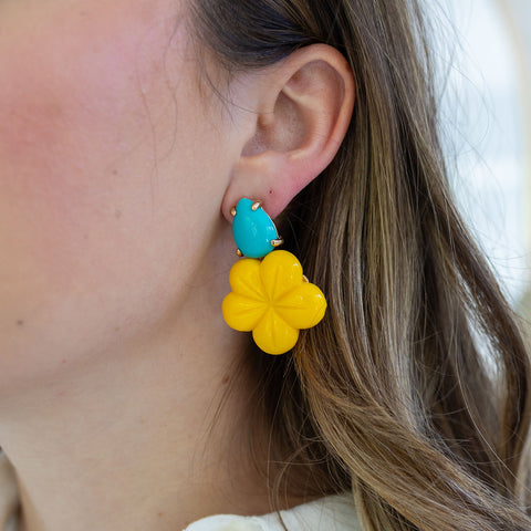 Picture of a woman wearing yellow flower earrings topped with a turquoise teardrop.