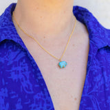 Picture of model wearing a a blue shirt and a fine gold chain with a blue turquoise elephant pendant.