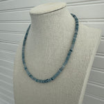 Picture of a display showing a slate blue bead necklace.