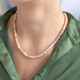 Woman wearing a short necklace with cream colored resin beads and gold spacer beads