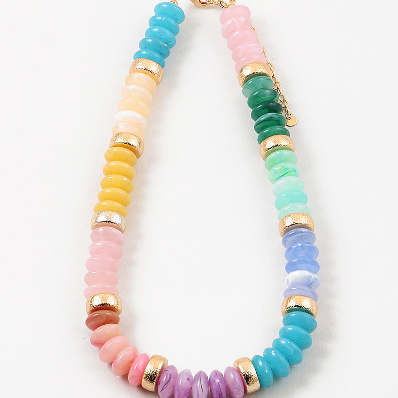 Picture of a chunky beaded necklace in greens, blues, inks and yellows. Necklace has a gold accent bead every 5th bead.