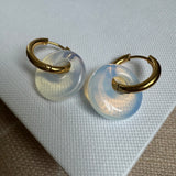 Small gold hoops threaded through a large white opaque disc bead