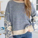 Person wearing a blue and white striped sweater with floral details in a casual setting.