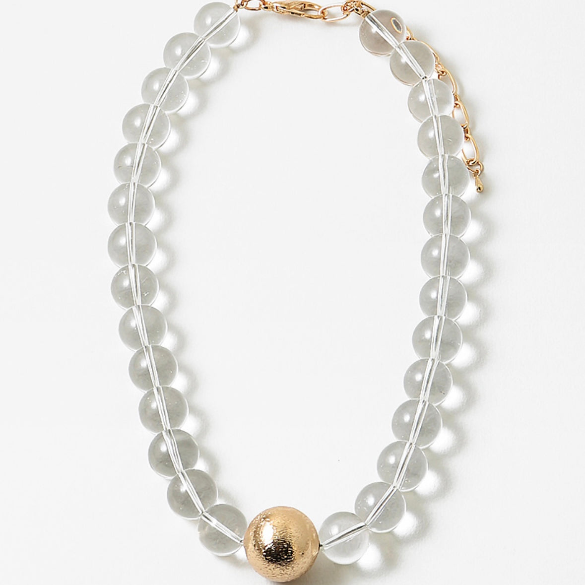 Necklace with clear beads and a gold ball pendant on a white background