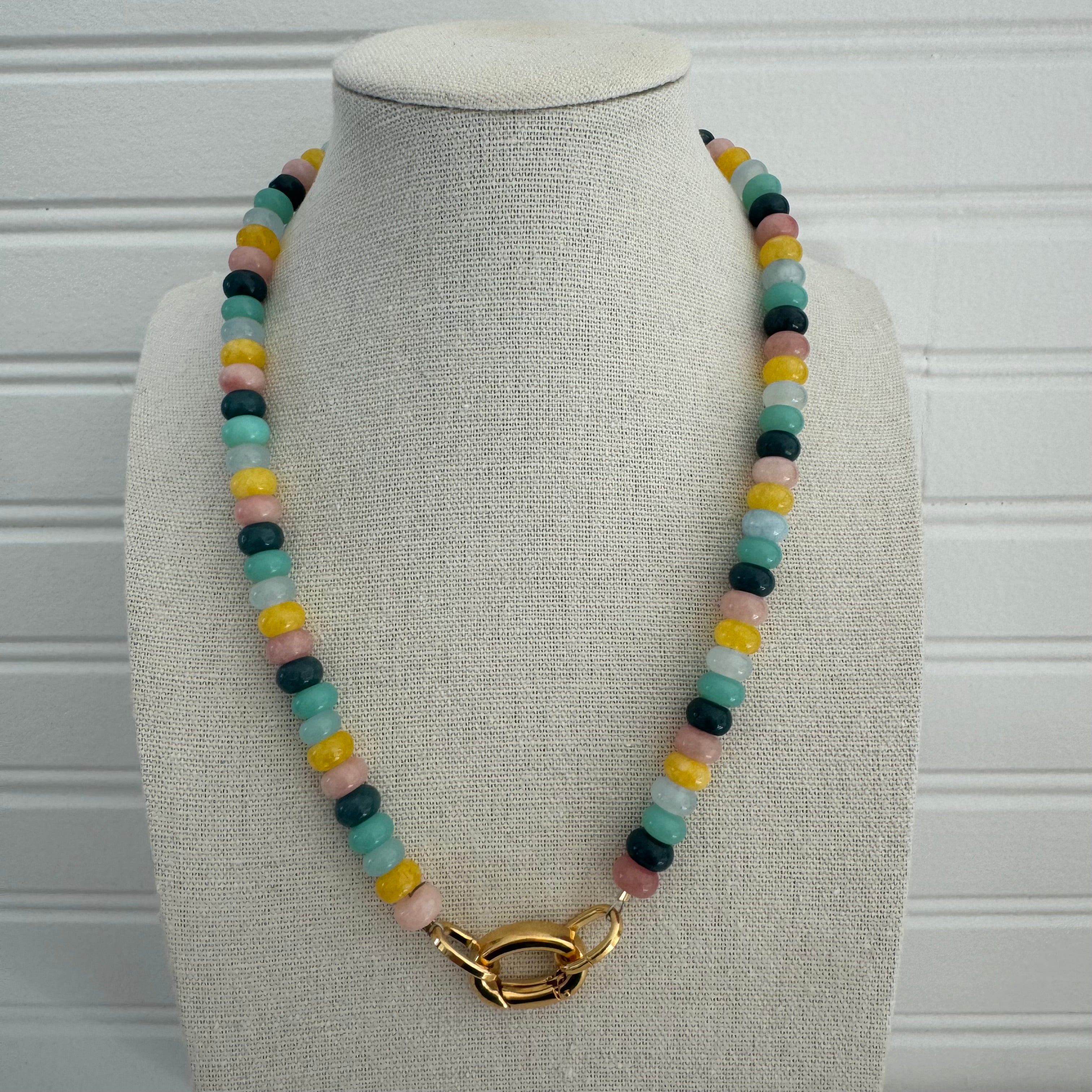 Picture of a necklace made of green, blue, white, yellow and pink beads with a large gold carabiner clasp.