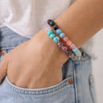 Colorful beaded bracelets on a wrist with denim jeans in the background