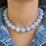 Light blue chunky beaded necklace worn by a person with denim clothing.