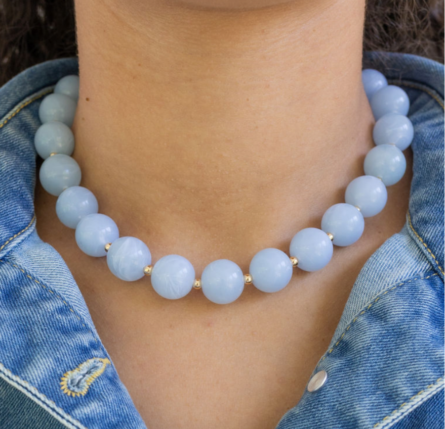 Light blue chunky beaded necklace worn by a person with denim clothing.